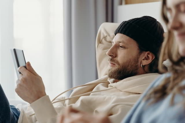 A man and a woman lying down in a relaxed way reading from a Tablet PC